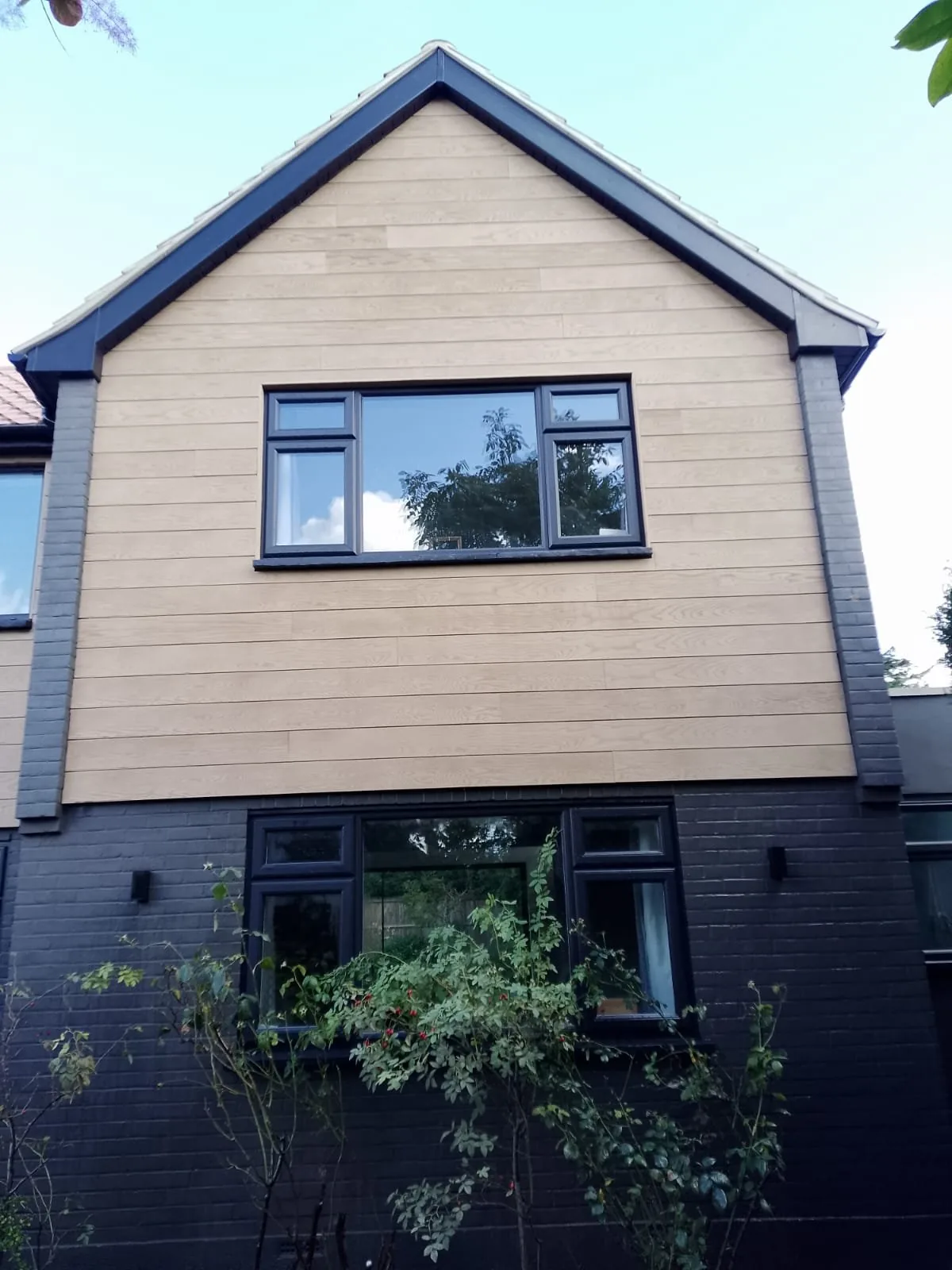 Gable end finished with dark fascia, bargeboards and cladding beneath a tiled roof