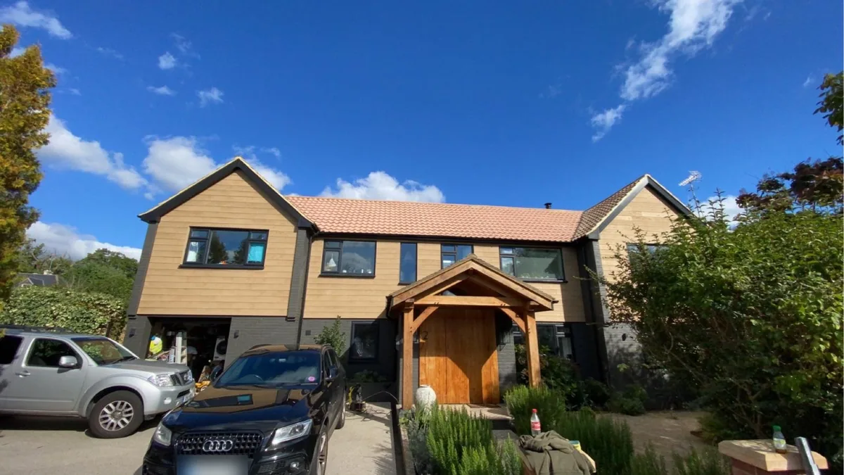 Finished house re-roofed by Rayner’s Roofing with new tiled roof, dark roofline, cladding and oak porch